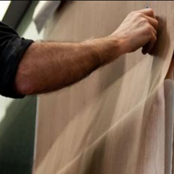 Installer smoothing woodgrain architectural film onto a wall panel